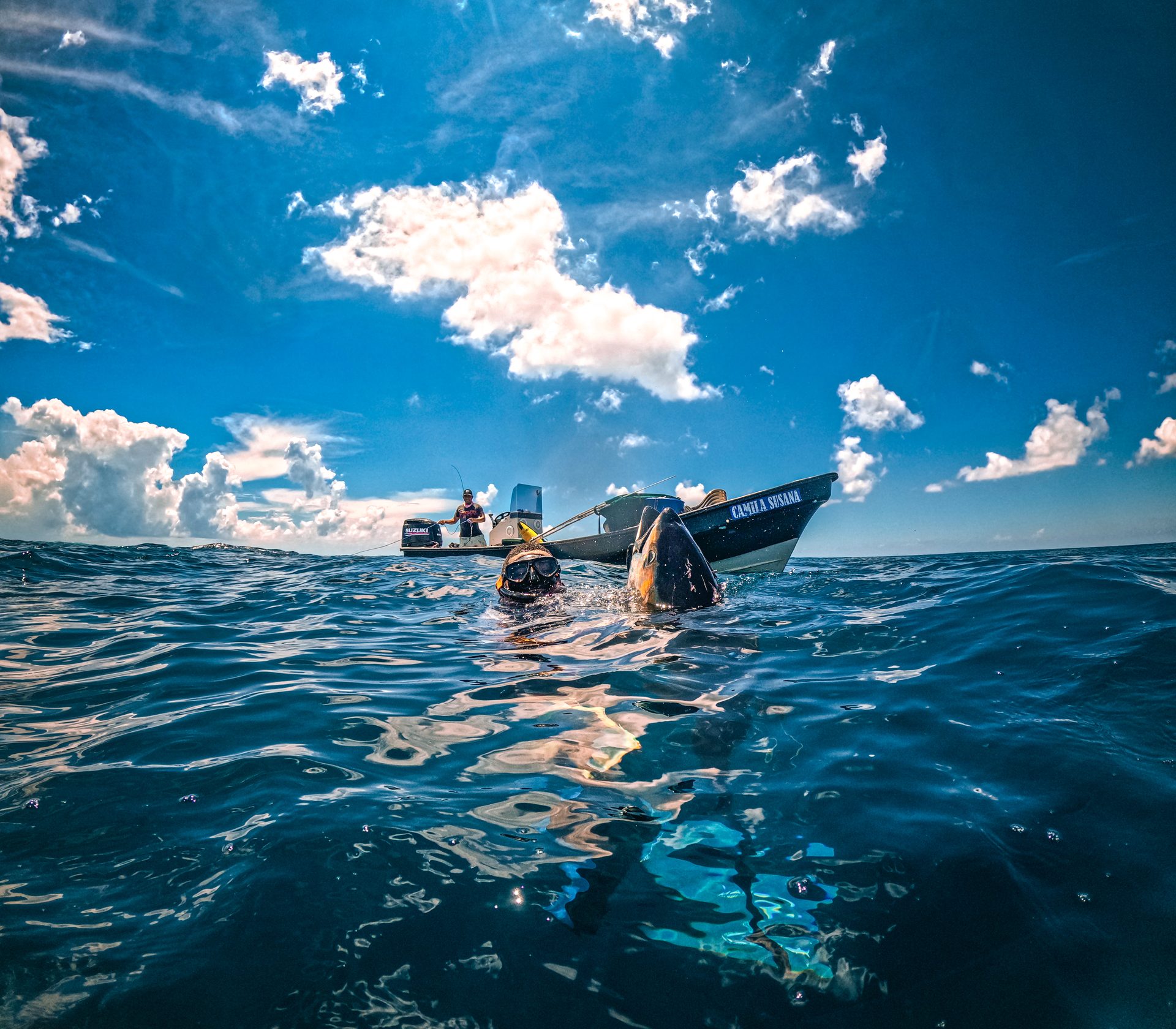 Spearfisher at the surface with yellowfin tuna next to the fishing boat, Pacific Panama